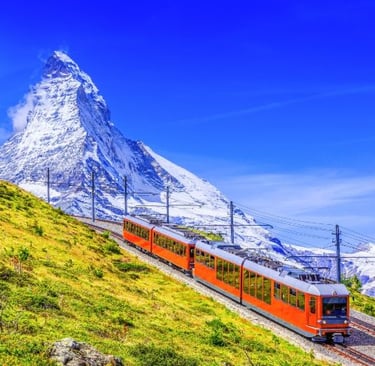 a train traveling down a mountain with a mountain in the background