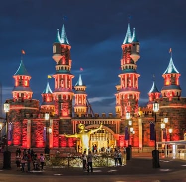 a fairytale castle in a theme park with a clock tower in the middle of it
