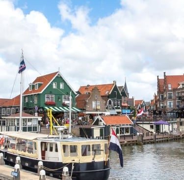 Traditional Dutch houses and boats in the historic Volendam harbor under a cloudy sky.