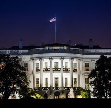 the white house at night with the american flag flying in the sky