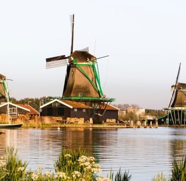 Traditional Dutch windmills along the river at Zaanse Schans in the Netherlands during sunset.