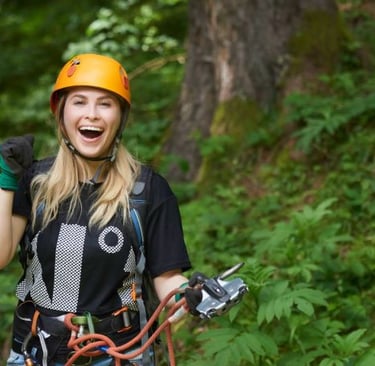 a woman in a helmet and safety gear on a zipline