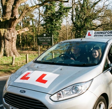Driving school car with L plates driving along a road in Chingford.