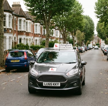 Learner car taking Chingford driving lessons on a quiet residential street.
