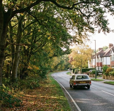 Car driving on a road near Loughton, transitioning between forest and residential areas