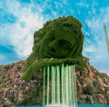 a giant green statue of a man with a waterfall in the background