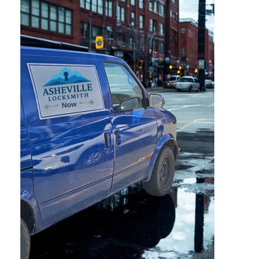 Blue Asheville Locksmith Now service van driving through West Asheville on rainy day