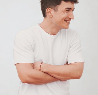 Smiling young man in a classic white crew neck t-shirt and red trousers posing with arms crossed.