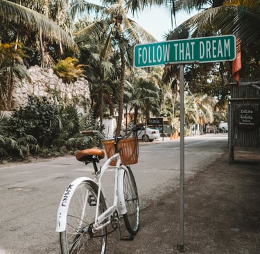 Vintage bicycle leaning against a pole with a 'Follow Your Dreams' sign