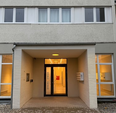 Modernisierter Eingangsbereich eines Wohngebäudes mit Glasfront und Leuchtbeschriftung