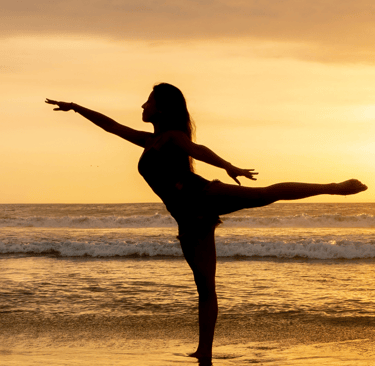 a woman is standing on a beach with her legs up in the air