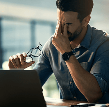 a man sitting at a desk with a laptop and glasses