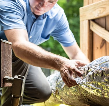 Nathan Smith moving a piece of Ductwork into a crawlspace