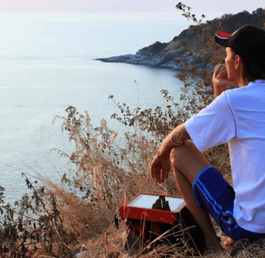 a man sitting on a hill with a tablet computer