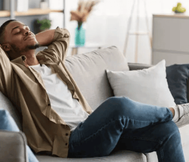 a man sitting on a couch with his head resting on his hands