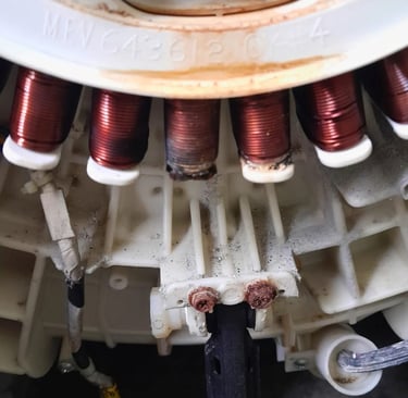 Close-up of damaged LG washer stator with visible burn marks and corrosion – associated with LE erro