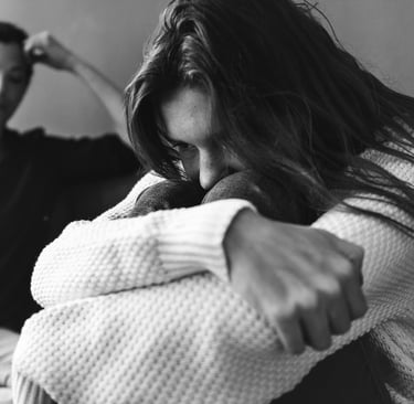 Jeune femme assise, recroquevillée et préoccupée, exprimant un profond malaise émotionnel, avec une