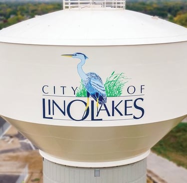 Aerial view of the City of Lino Lakes water tower featuring a blue heron logo and local landscape.