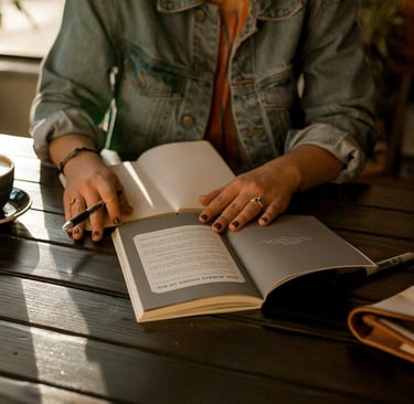 Image of a woman writing a book on a park table