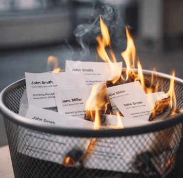 Business cards burning in a bin symbolizing unusable or outdated contact data