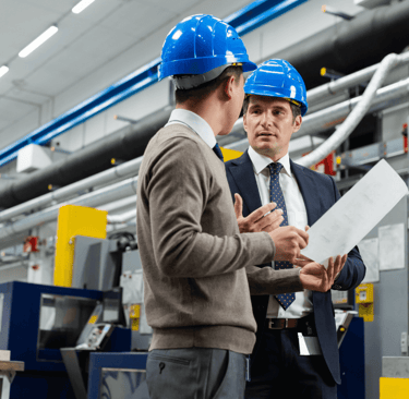 Engineers discussing plans on a factory floor