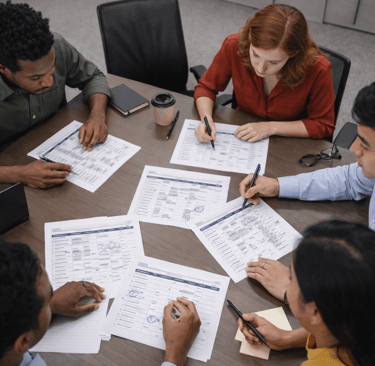 SDR team reviewing printed B2B lead sheets with missing metadata fields at a conference table