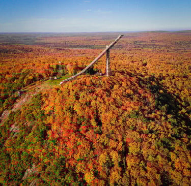 Tall Copper Peak ski jump structure in Ironwood, Michigan, surrounded by brilliant autumn trees.