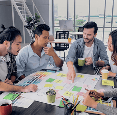 a group of people sitting around a table with papers and coffee