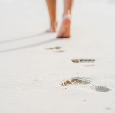 pieds nus laissant des empreintes sur le sable symbolisant le cheminement personnel en sophrologie