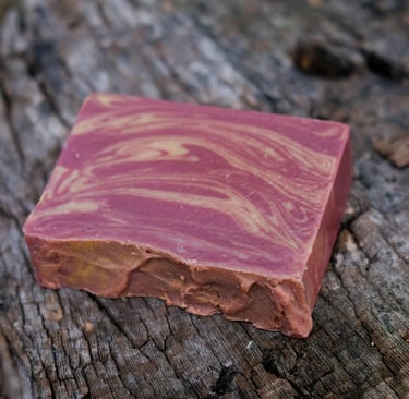 a soap bar with a burgundy and gold swirl design on a tree stump