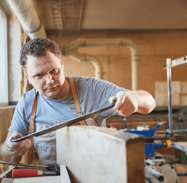 a man in a workshop with a drawknife