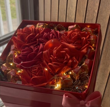 a person holding a red box with roses in it