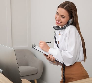Une femme, assistante administrative au teléphone, devant son ordinateur, à l'accueil,