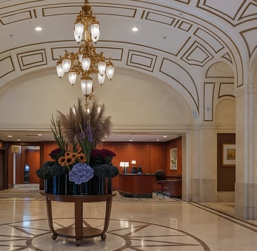 Luxurious hotel lobby with a round floral centerpiece featuring pampas grass and hydrangeas beneath a gilded chandelier