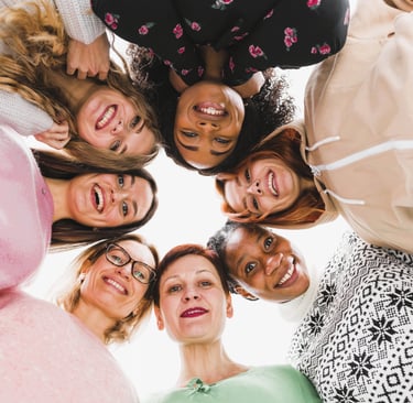 Une cercle de femmes souriantes qui regardent l'objectif en plongée. 