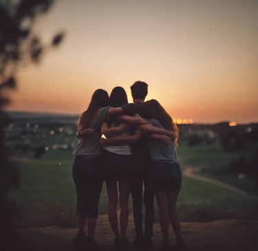 four person hands wrap around shoulders while looking at sunset