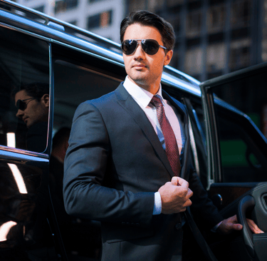 Man in a suit stepping out of a black car for a negotiation.