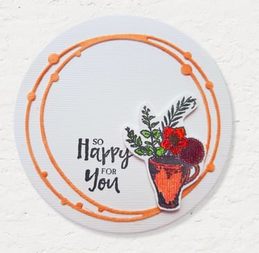A round card with an orange circle border features a painted orange mug filled with green leaves and