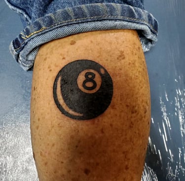 Black 8 ball tattoo on the back of a calf