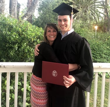 a smiling Nicole hugging Jackson in his graduation gown, holding his diploma