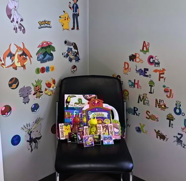 Picture of consult room with stickers on the wall and a chair filled with children's items
