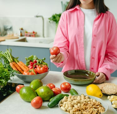 person holding a tomato while having vegetables on the kitchen counter 