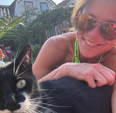 lachende vrouw met zonnebril met die een zwart witte kat aait