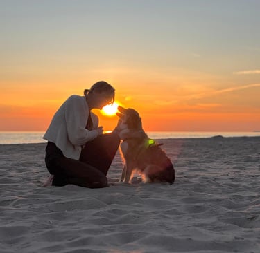 Vrouw en hond op het strand met ondergaande zon