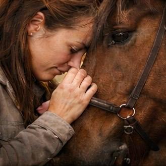 Vrouw met haar hoofd tegen paarden hoofd