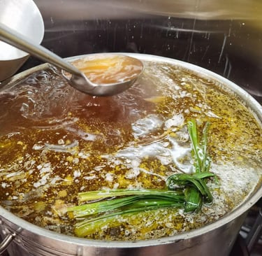 a picture of pho being cooked with a spoon of broth being taken out