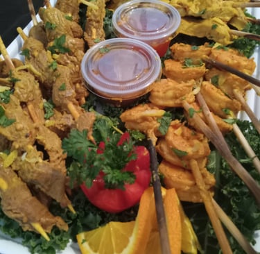 a platter of food with chicken, beef and shrimp satays
