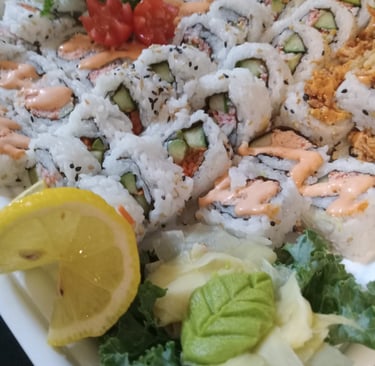 a plate of sushi rolls with a lemon wedged in the middle