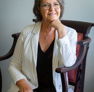  Joëlle Dechamplain assise, souriante, en veston rayé, incarnant l’accompagnement humain du deuil. 