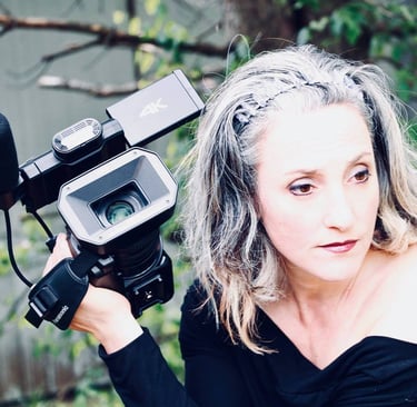 Micheline Brulotte filme avec une caméra professionnelle dans un décor extérieur naturel.